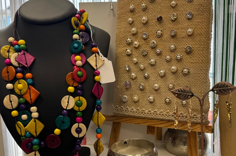 collier fantaisie multicolore, bracelet argenté et présentoirs de nombreuses boucles d'oreille